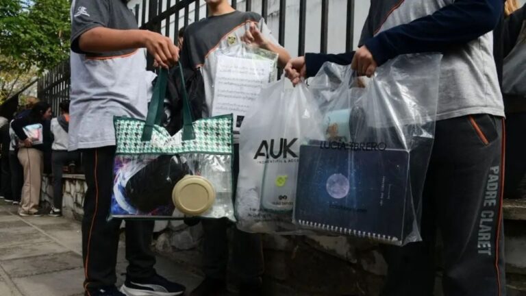 Estudiantes ingresando a una escuela con bolsas transparentes en lugar de mochilas.