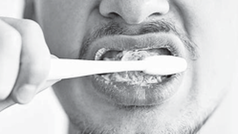 Persona cepillándose los dientes frente a un espejo por la mañana