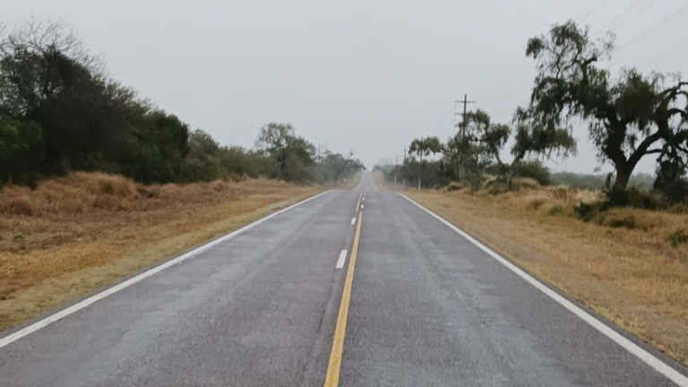 Ruta Nacional 64 con lluvia y señal de precaución