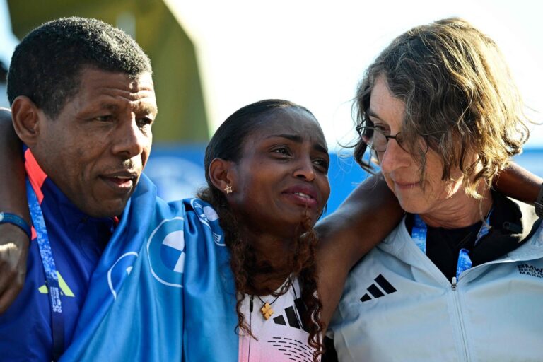 Tigst Assefa cojeando en la meta de la Maratón de Berlín bajo la Puerta de Brandeburgo